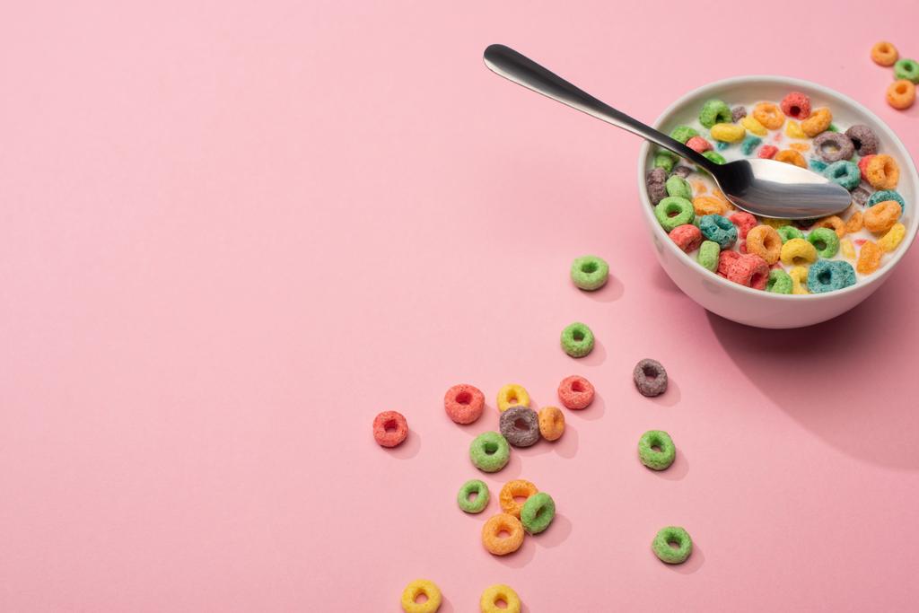 ピンクの背景にスプーンでボウルにミルクと明るいカラフルな朝食シリアル - 写真・画像