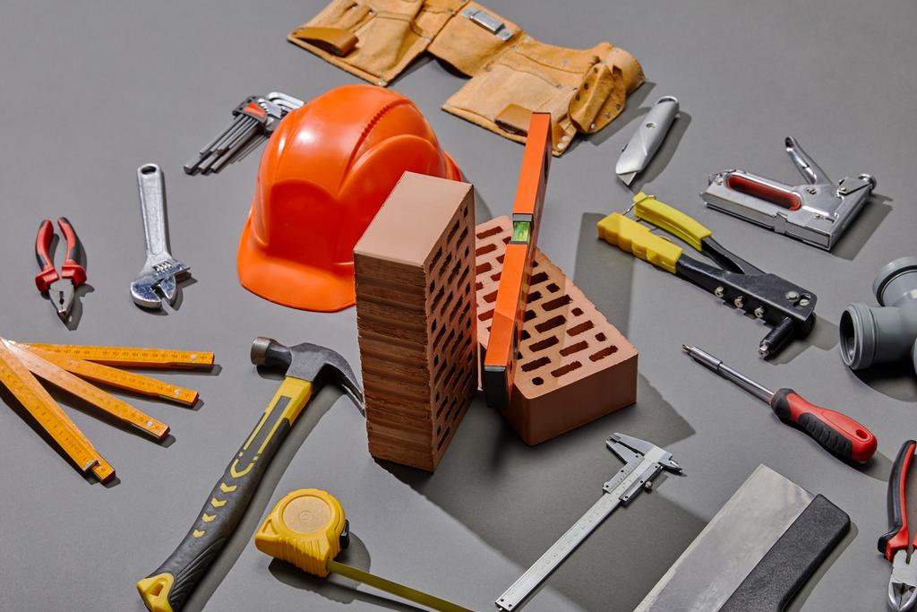 high angle view of helmet, bricks and industrial tools on grey background - Photo, Image