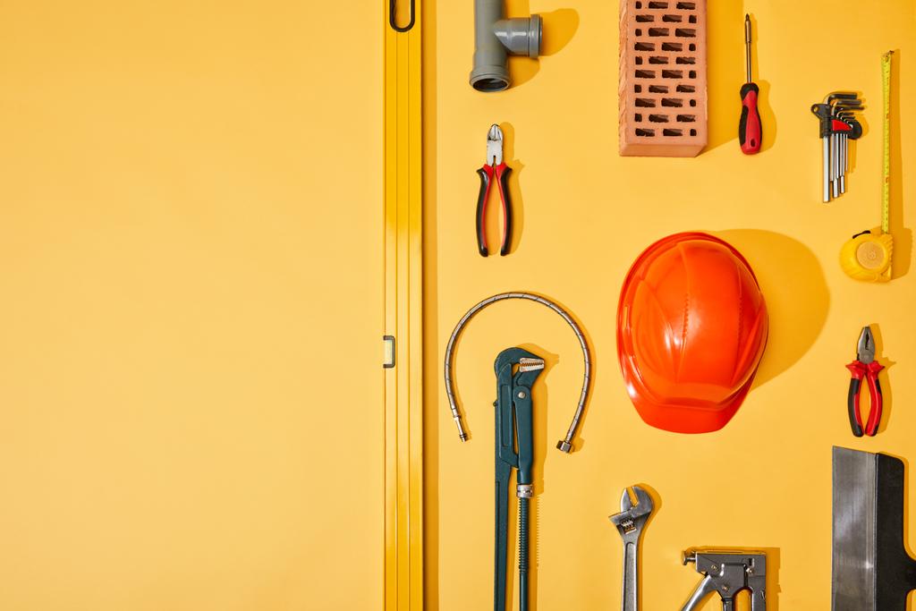 tendido plano con herramientas industriales, cinta métrica y casco, sobre fondo amarillo
 - Foto, Imagen