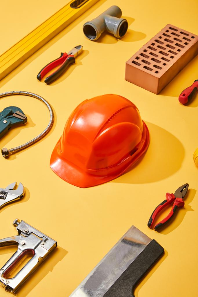 flat lay with industrial tools, helmet and brick, on yellow background - Photo, Image