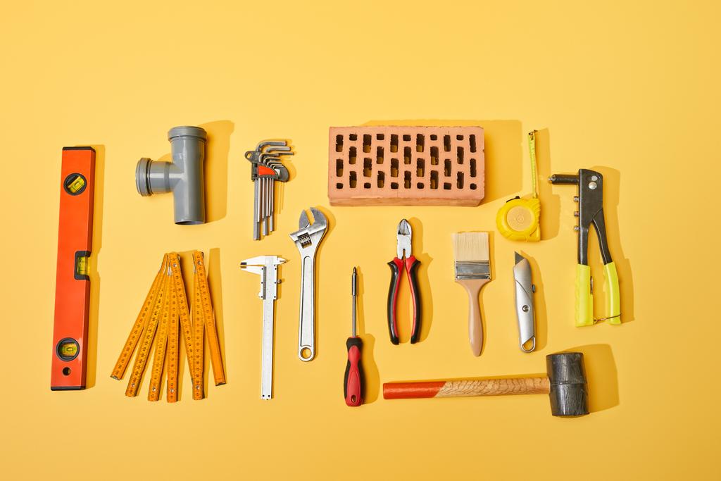 vista superior de herramientas industriales y ladrillo sobre fondo amarillo
 - Foto, Imagen