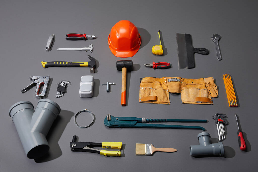 flat lay com ferramentas industriais, capacete e cinto de ferramentas em fundo cinza
 - Foto, Imagem