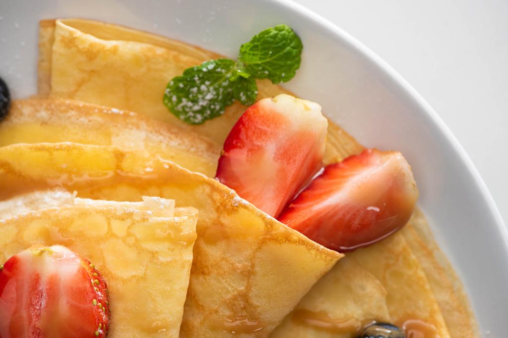 close up view of tasty crepes with strawberries and mint on plate - Photo, Image