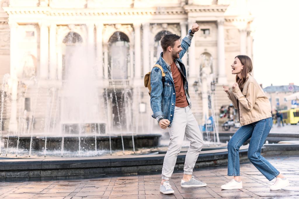 Возбужденные мужчина и женщина смотрят друг на друга возле фонтана в городе
 - Фото, изображение