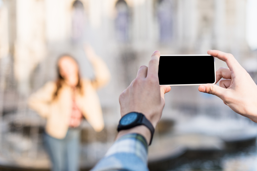 Vista cortada de homem tirando foto de mulher usando smartphone
 - Foto, Imagem