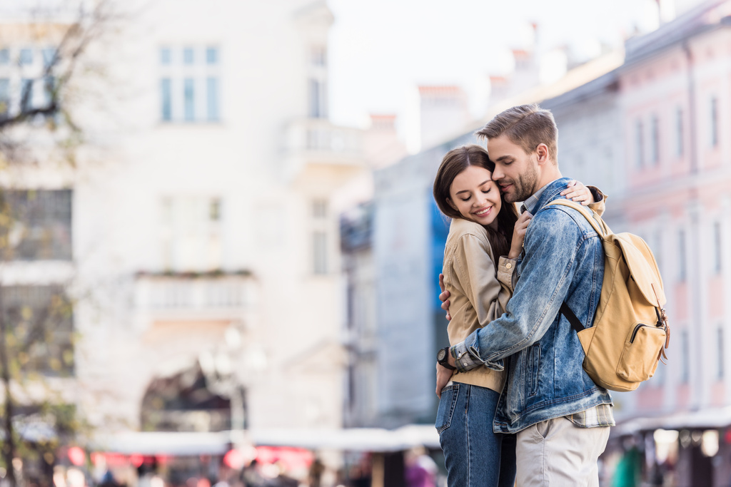 Novio y novia abrazándose con los ojos cerrados y sonriendo en la ciudad
 - Foto, Imagen