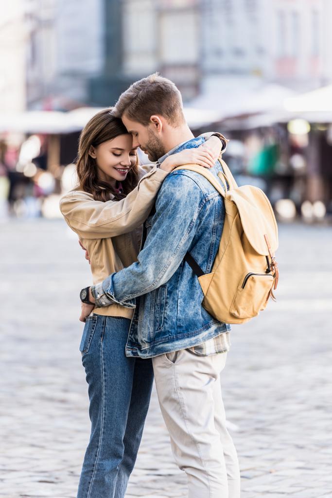 Sırt çantalı bir adam şehirde güzel bir kız arkadaşla kucaklaşıyor. - Fotoğraf, Görsel