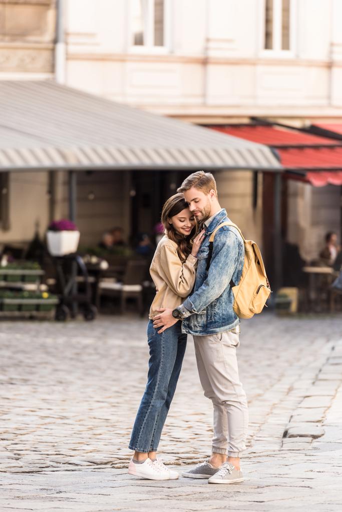 Glückliches Paar umarmt und lächelt mit Rucksack in Europas Städten - Foto, Bild