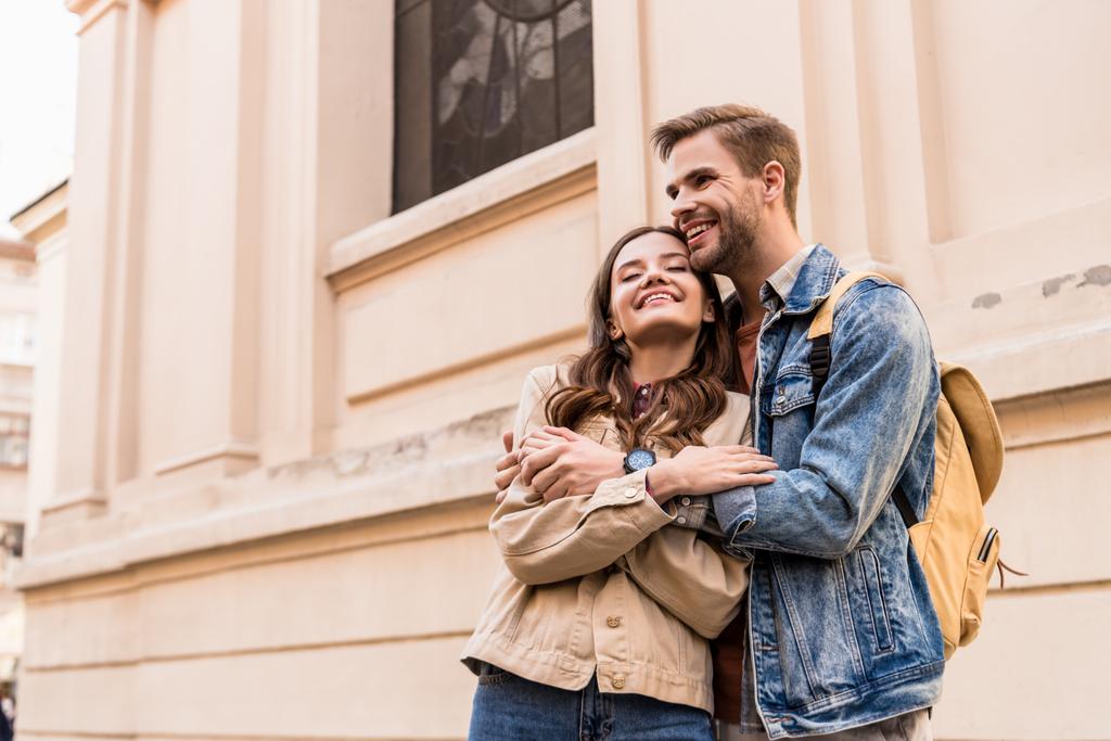 Muž a žena se zavřenýma očima objímající a usmívající se ve městě - Fotografie, Obrázek