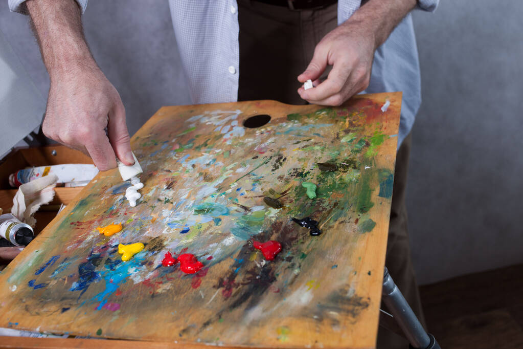 画家はパイプからパレットに絵具を絞る。閉鎖 - 写真・画像