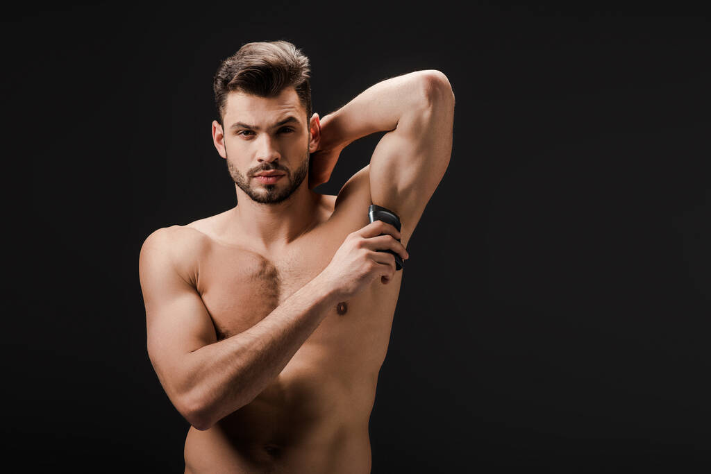 sexy hombre desnudo aplicando desodorante en axila aislado en negro
 - Foto, Imagen