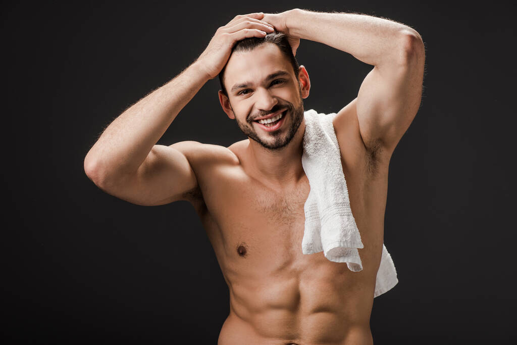 hezký usmívající se nahý muž s ručníkem izolované na černé - Fotografie, Obrázek
