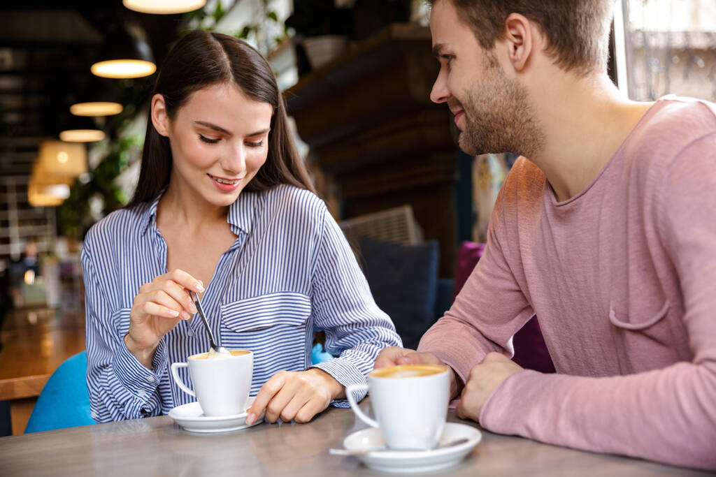 Привлекательная молодая пара влюблена, обедает в кафе в помещении, пьет кофе
 - Фото, изображение