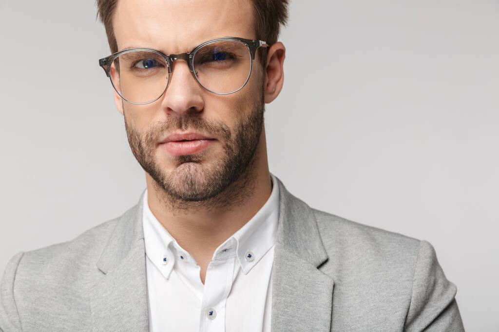 Valkoihoisen nuoren miehen muotokuva silmälaseissa poseeraa ja katselee kameraa valkoisella taustalla
 - Valokuva, kuva