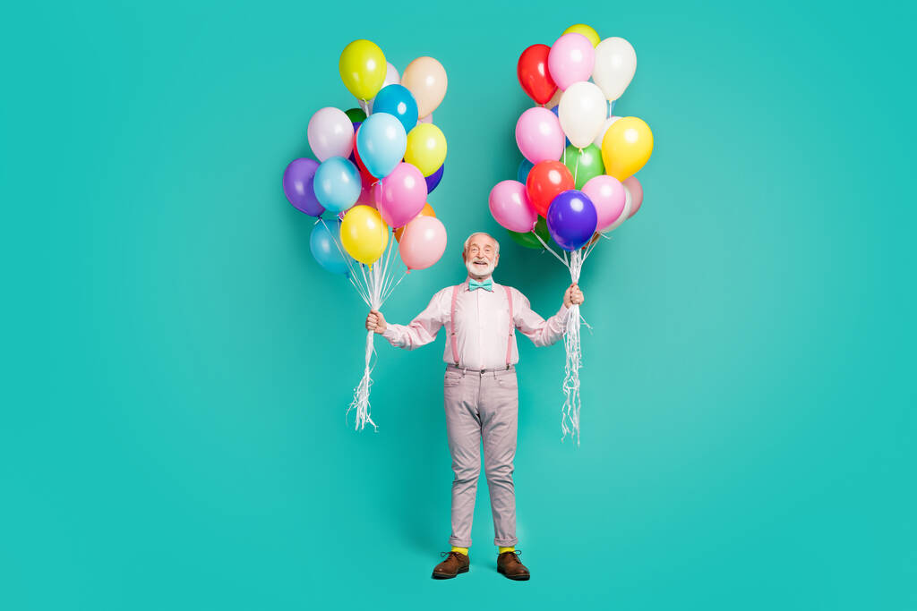 Full size photo of positive cheerful old man hipster hold many air balls enjoy festive occasion event wear good look trousers brown shoes isolated over teal color background - Fotografie, Obrázek