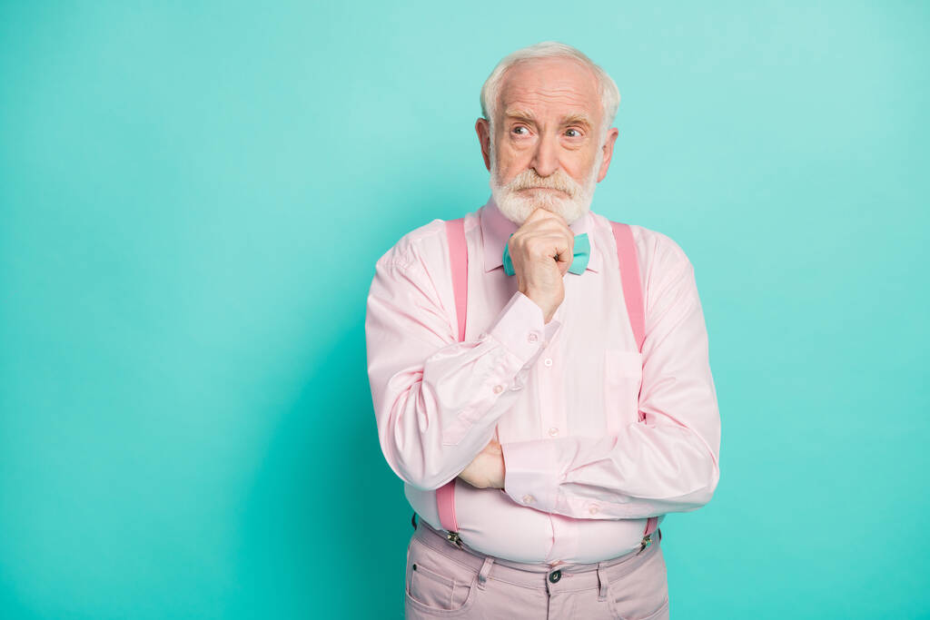 Photo of serious stylish grandpa hold arm on chin look side empty space deeply minded wear pink shirt suspenders bow tie pants isolated bright teal color background - Fotografie, Obrázek