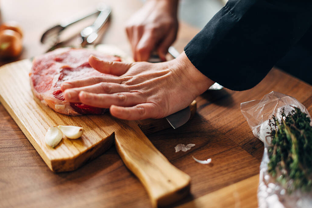 Boven schot van chef-kok het bereiden van ribeye in een keuken - Foto, afbeelding