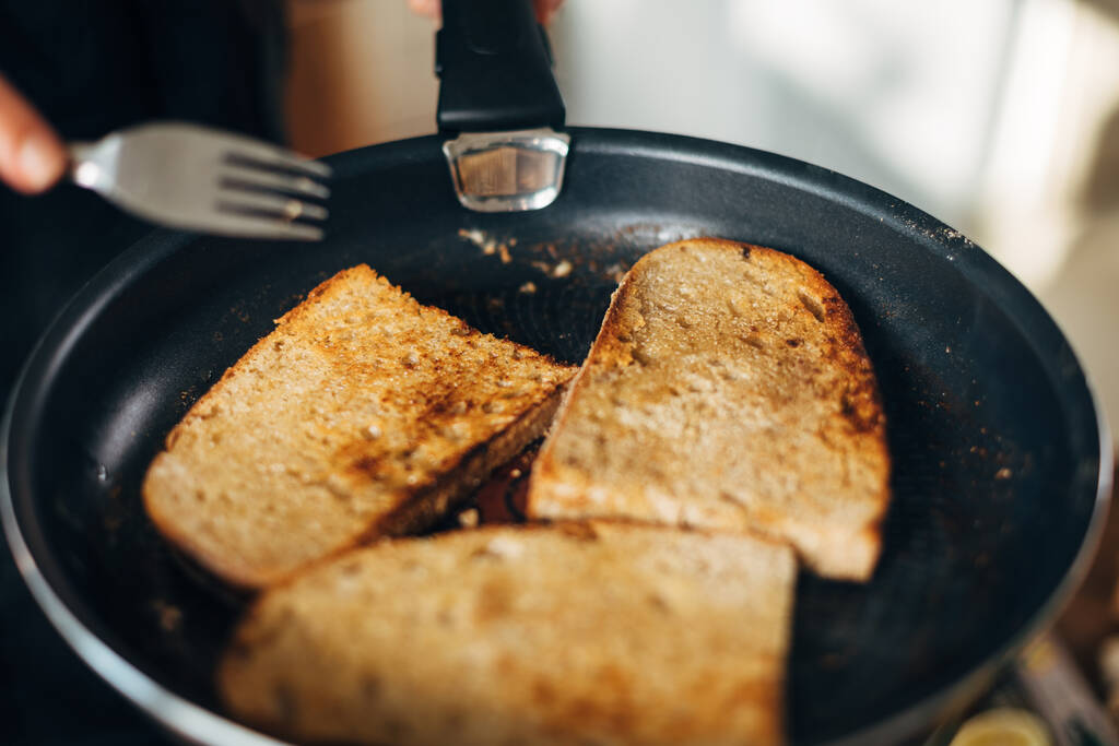 Chef tostando pan integral en una sartén con mantequilla
 - Foto, Imagen