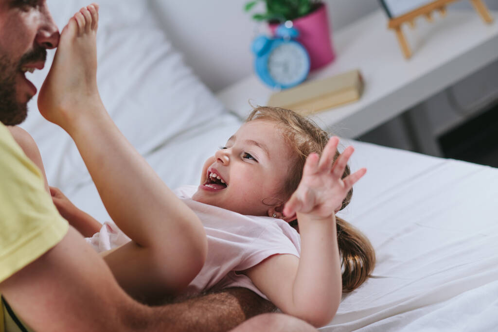 vader en dochter spelen op bed - Foto, afbeelding
