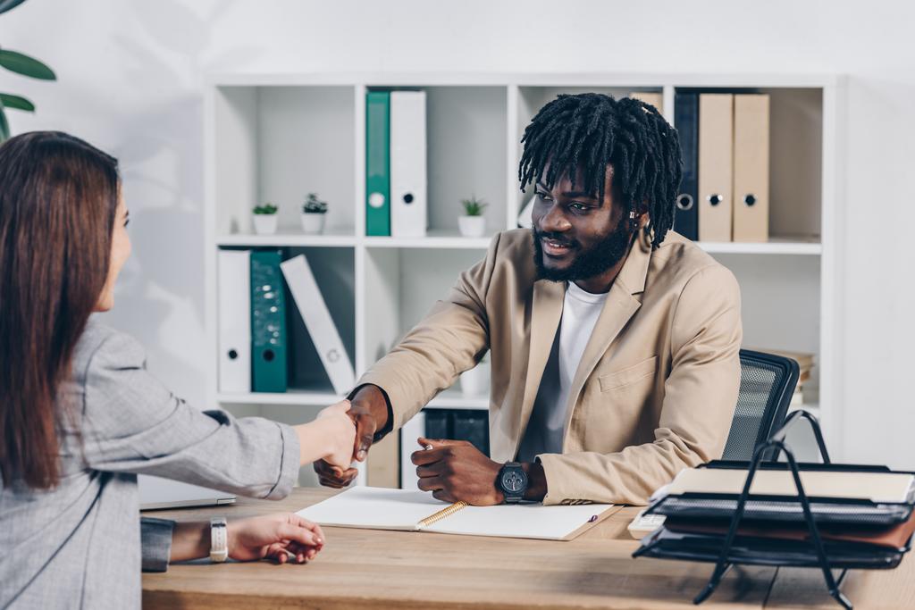 African american recruiter shaking hands with employee at job interview in office - Photo, Image