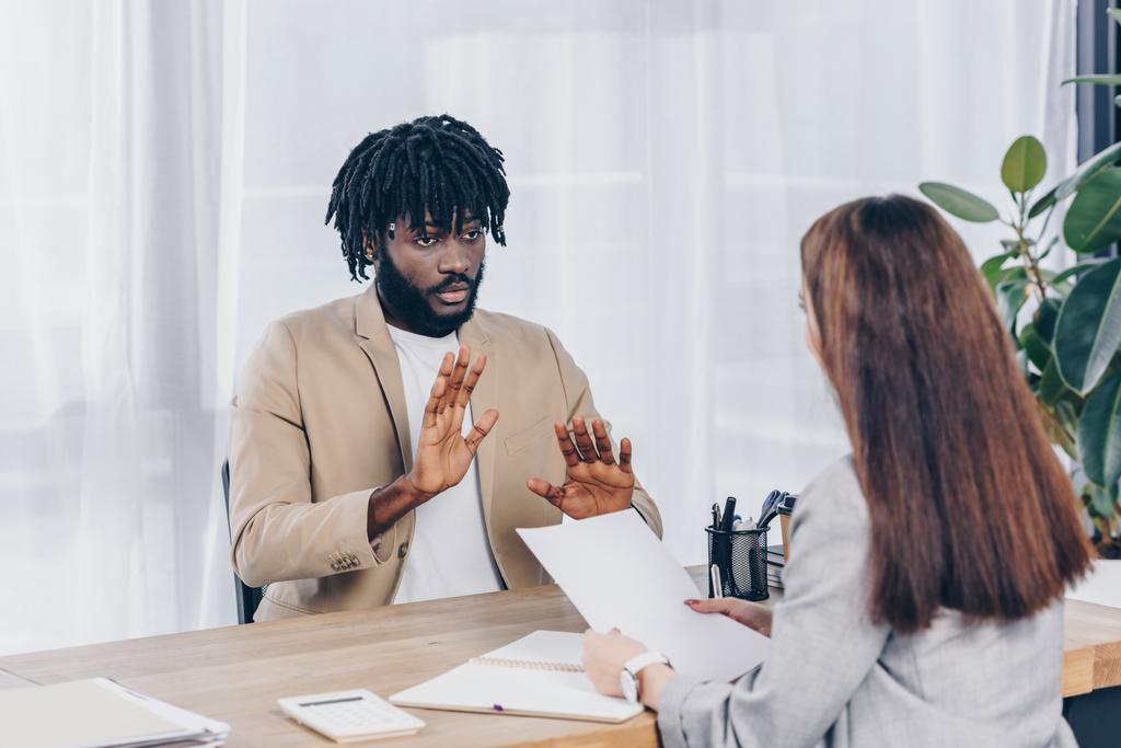 Selektywna koncentracja rekrutera z papierem i afrykańskim pracownikiem rozmawiającym na rozmowie kwalifikacyjnej w biurze - Zdjęcie, obraz