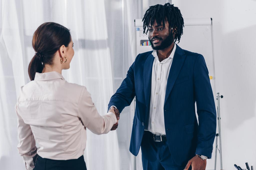 African american recruiter and employee shaking hands and looking at each other in office - Photo, Image