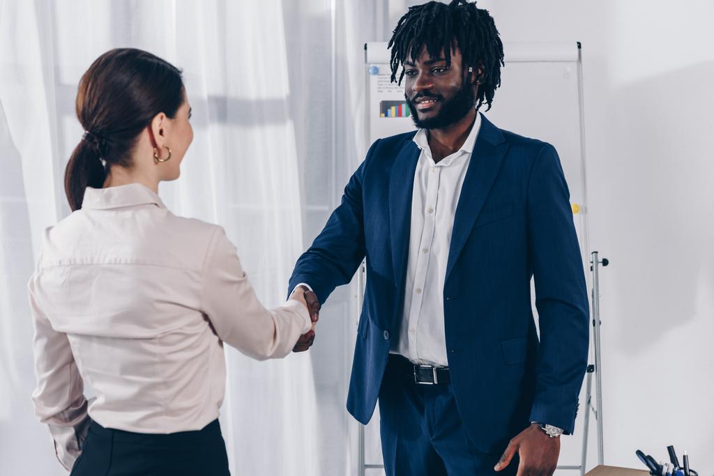 African american recruiter and employee shaking hands, smiling and looking at each other - Photo, Image