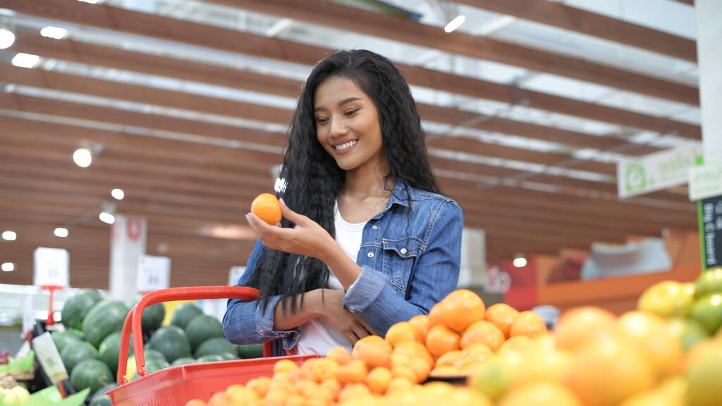 Winkelconcepten. Mooi meisje koopt fruit in het winkelcentrum. Resolutie van 4k. - Foto, afbeelding
