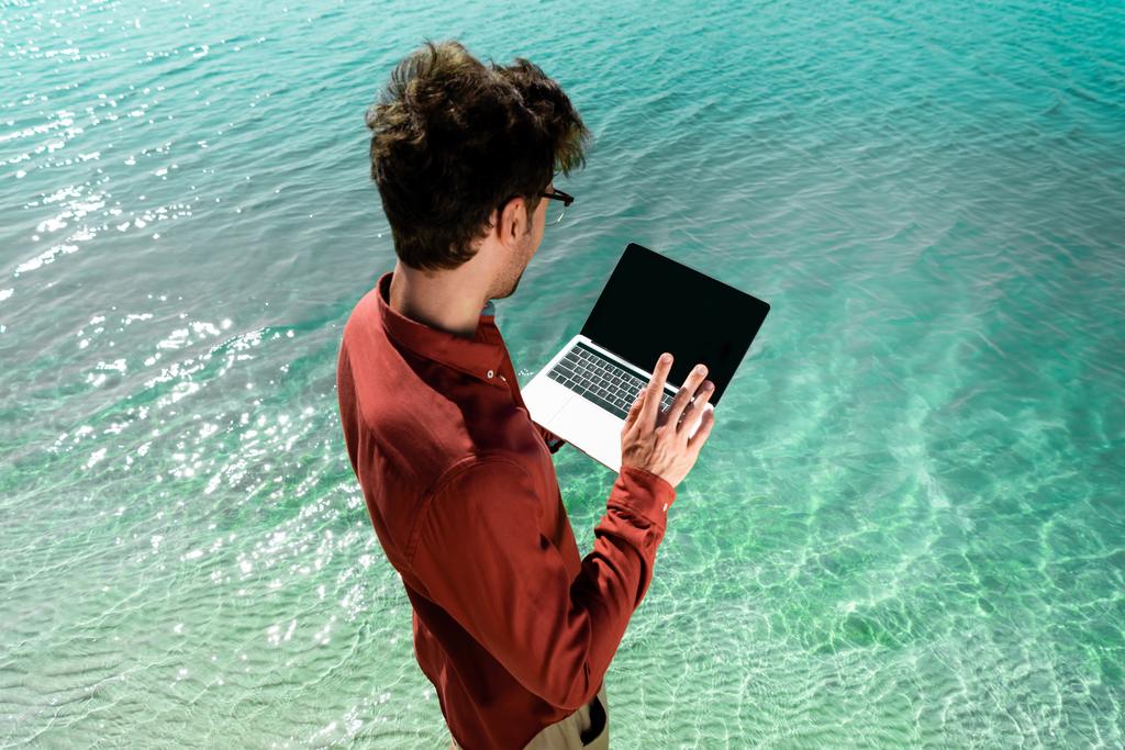 beau freelance avec ordinateur portable debout dans l'eau turquoise
 - Photo, image