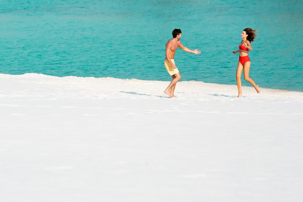 joven sexy pareja corriendo en arena playa cerca de océano
 - Foto, imagen