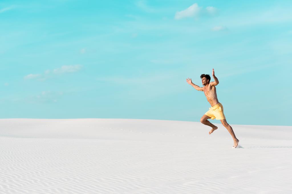 muž v plavkách kraťasy s svalnatým trupem běží na písečné pláži - Fotografie, Obrázek