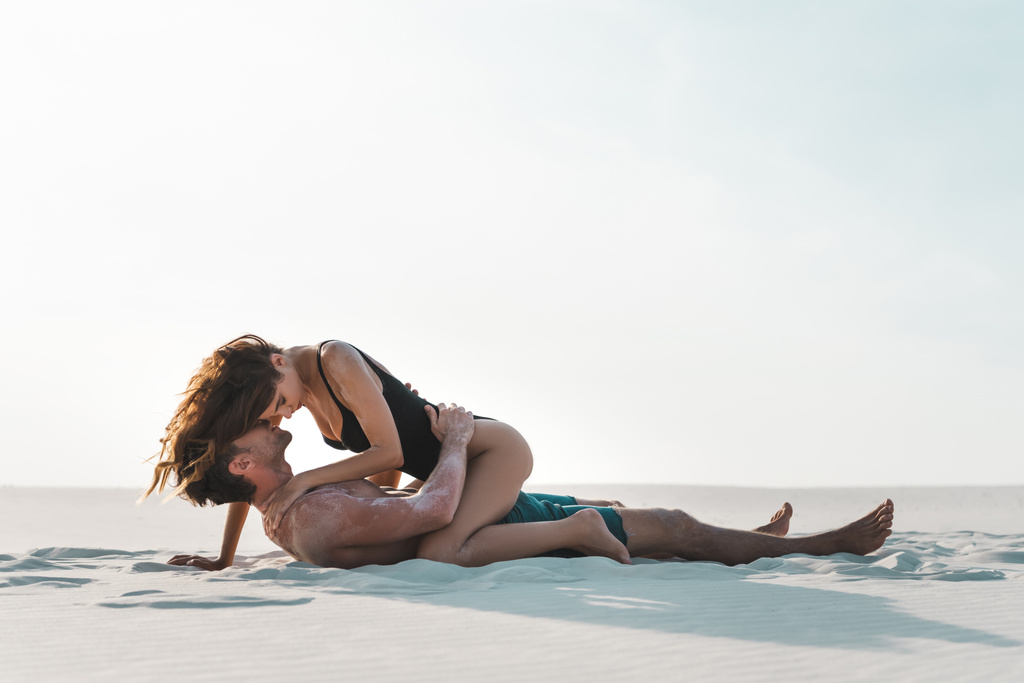 Seksi, tutkulu genç çiftin kumsalda yatışının yan görüntüsü.  - Fotoğraf, Görsel
