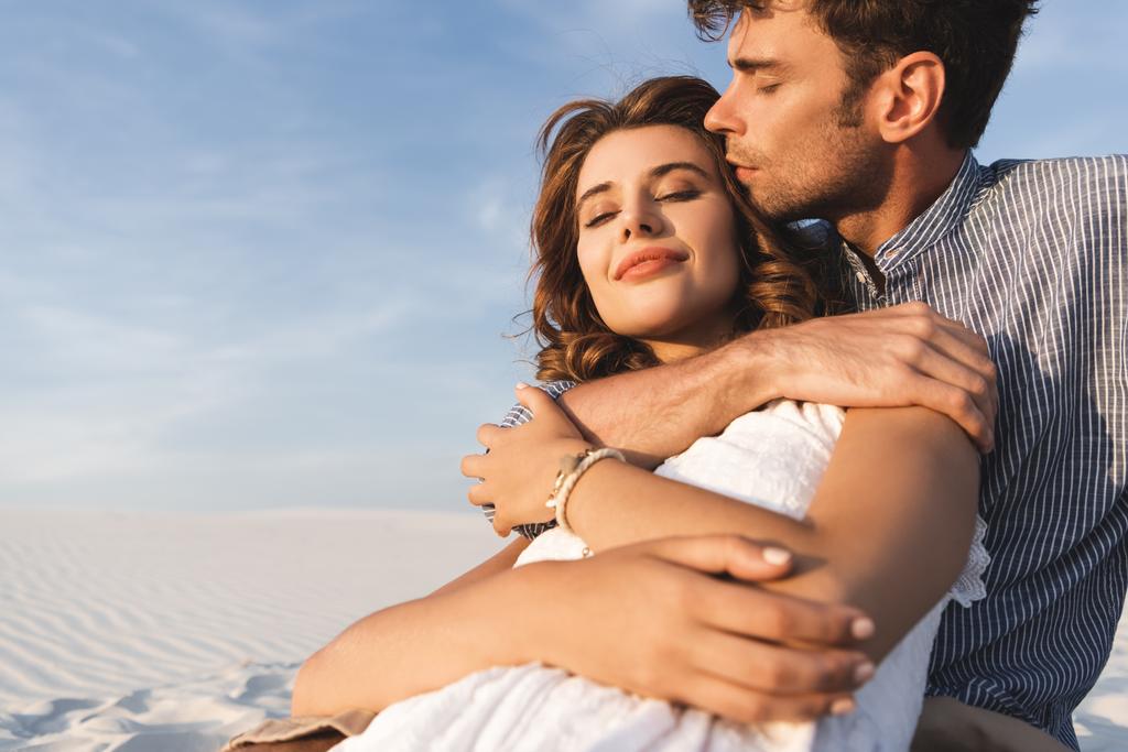 sonriente joven pareja abrazándose en la playa
 - Foto, imagen