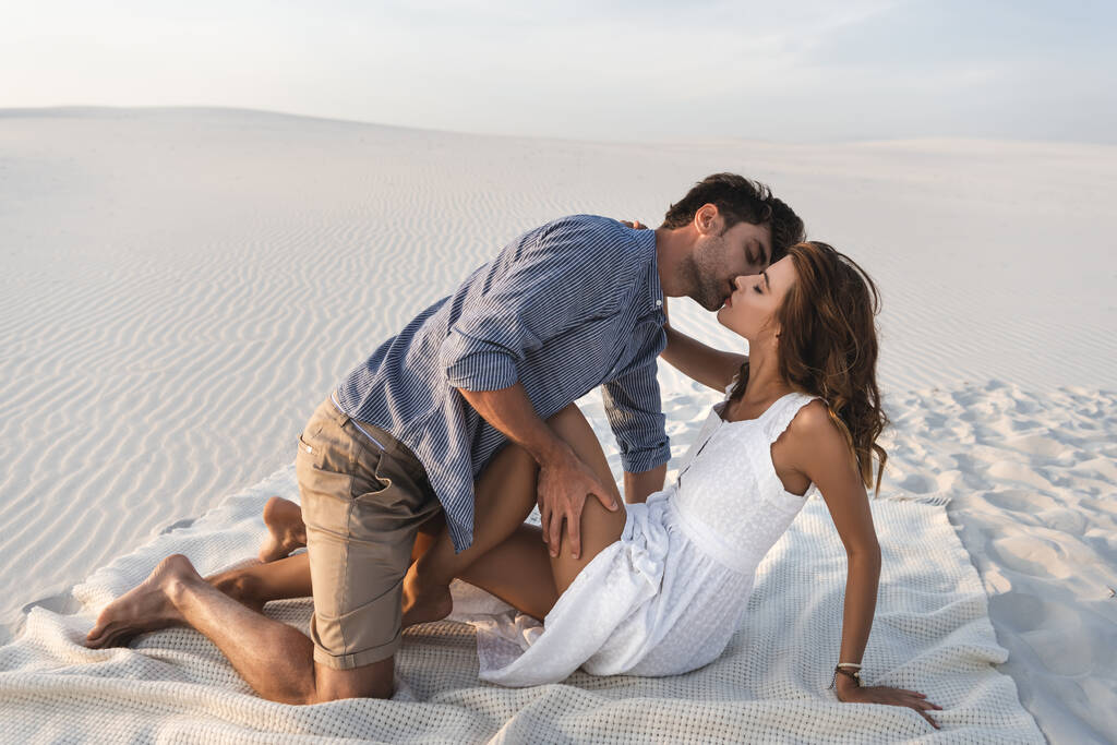 пристрасна молода пара цілується на ковдрі на пляжі
 - Фото, зображення