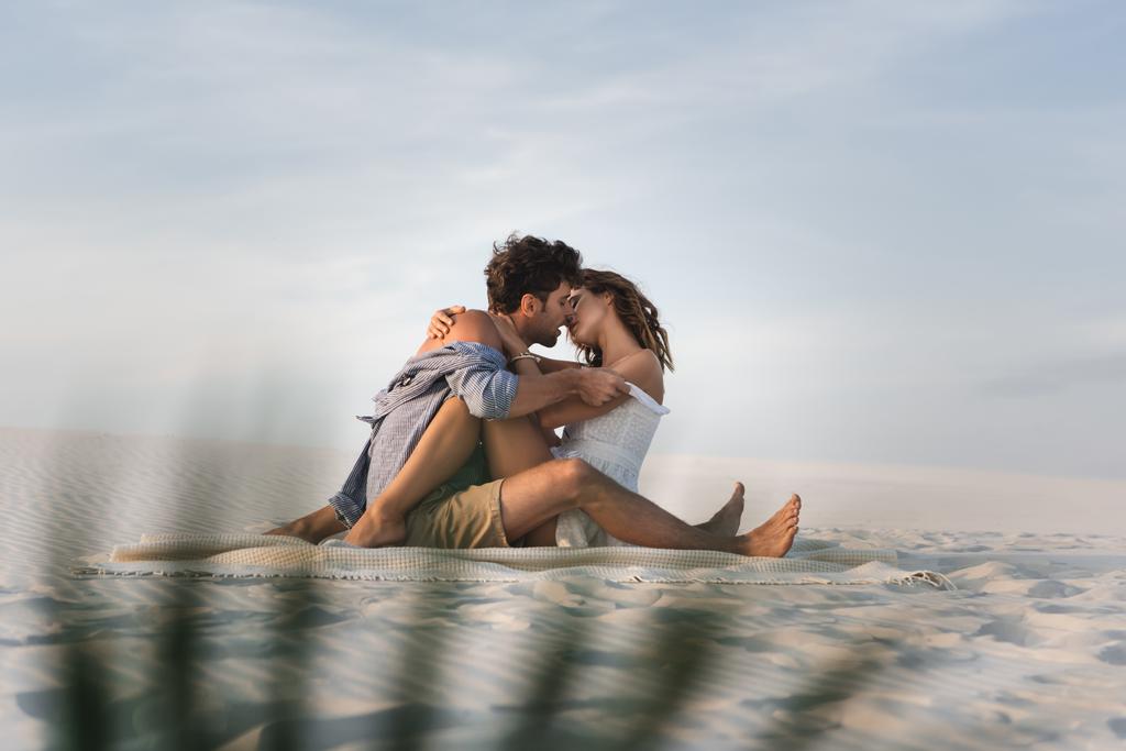 szelektív fókusz szenvedélyes fiatal pár csók takaró a strandon - Fotó, kép
