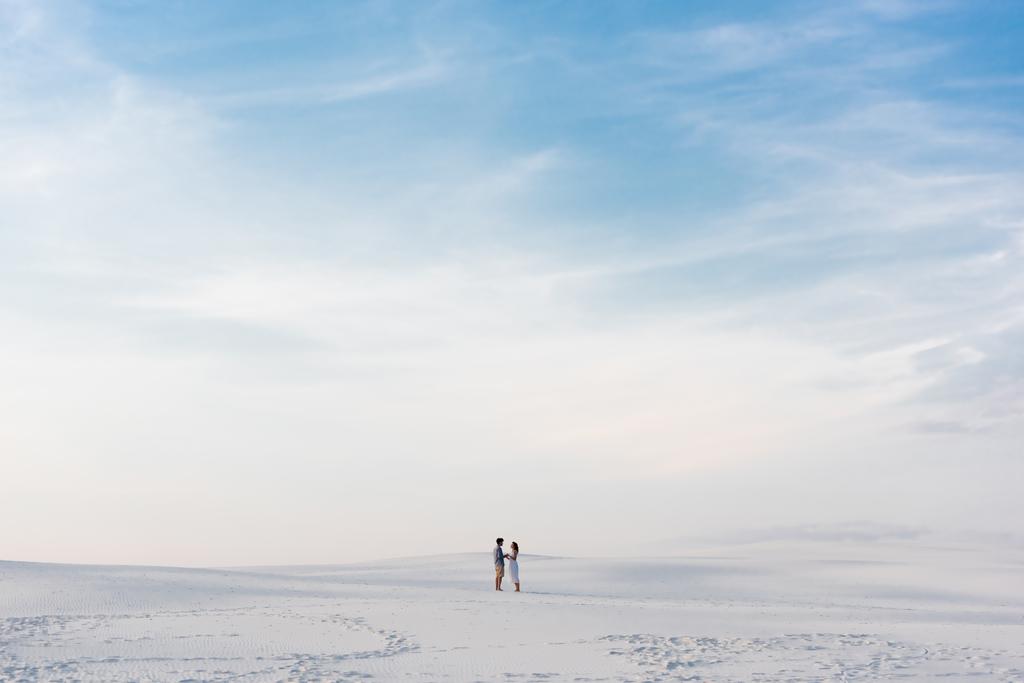 ζευγάρι στέκεται σε αμμώδη παραλία με γαλάζιο ουρανό - Φωτογραφία, εικόνα