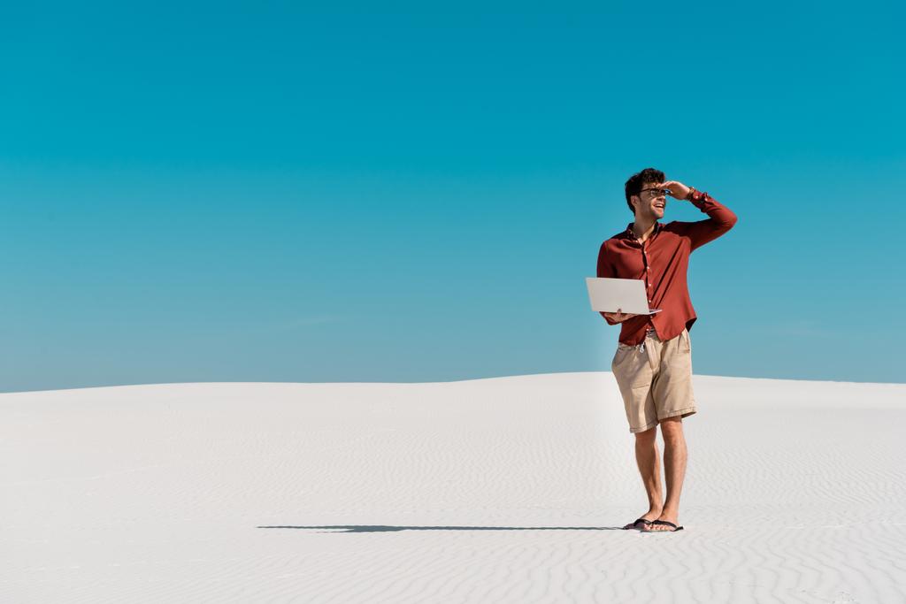 fiatal szabadúszó a homokos tengerparton laptop ellen tiszta kék ég - Fotó, kép