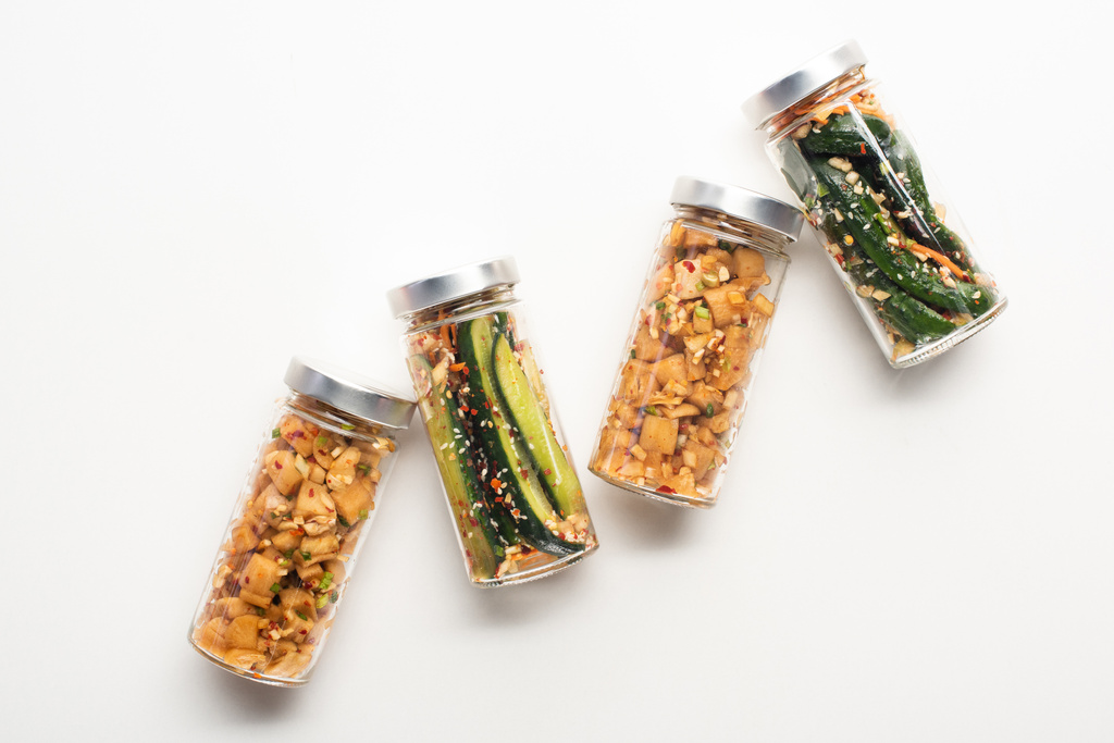 top view daikon retek és uborka kimchi üvegben fehér háttér - Fotó, kép