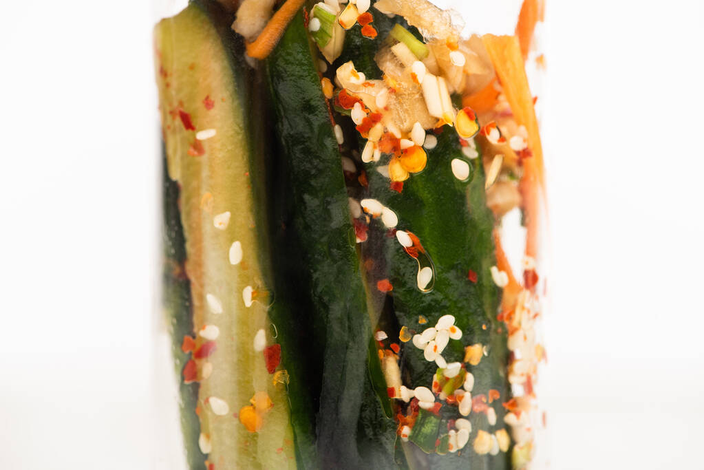 close up of tasty cucumber kimchi in glass jar isolated on white - Photo, Image
