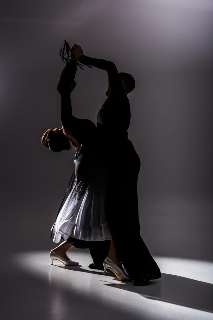 elegancka młoda para tancerzy towarzyskich w czarnym stroju taniec w ciemności - Zdjęcie, obraz
