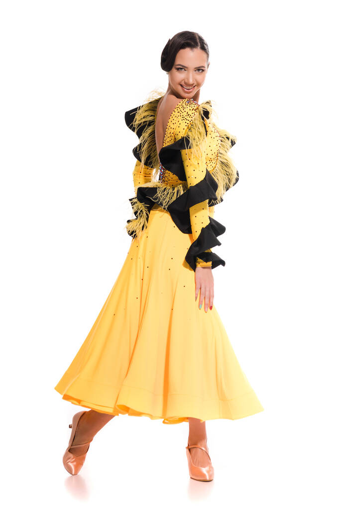 lächelnde elegante junge Standardtänzerin in gelbem Kleid, die isoliert auf Weiß tanzt - Foto, Bild