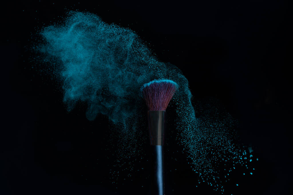Make-up Pinsel mit blauem Puder Explosion isoliert in einem schwarzen Hintergrund - Foto, Bild