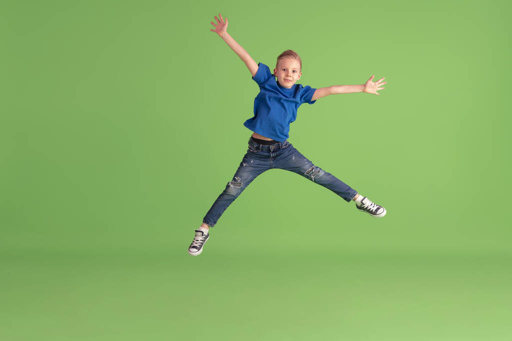 Boldog fiú játszik és szórakozás zöld stúdió háttér, érzelmek - Fotó, kép