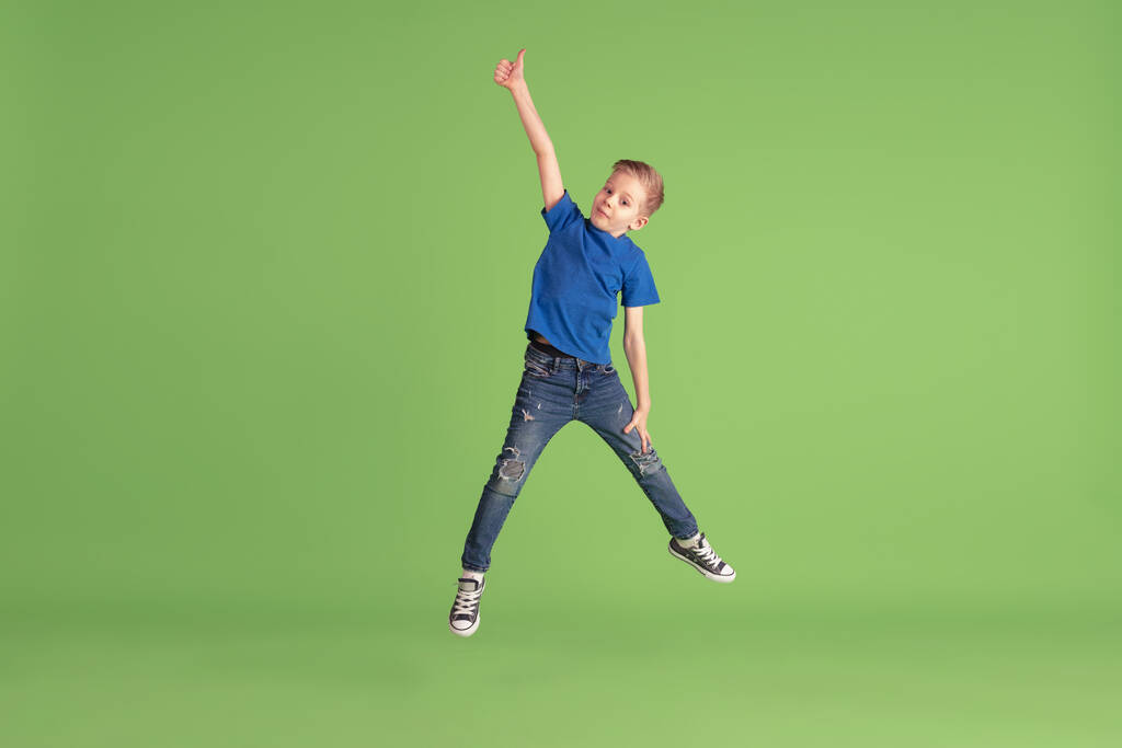 Ευτυχισμένο αγόρι παίζει και διασκεδάζει στο πράσινο φόντο στούντιο, συναισθήματα - Φωτογραφία, εικόνα
