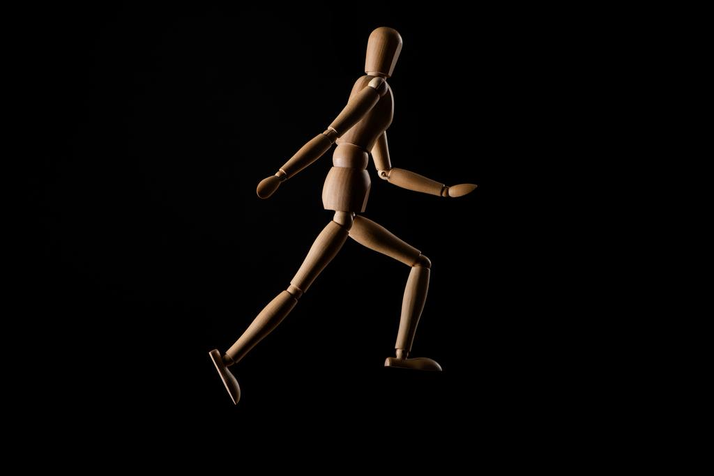 Wooden doll imitating running isolated on black  - Photo, Image