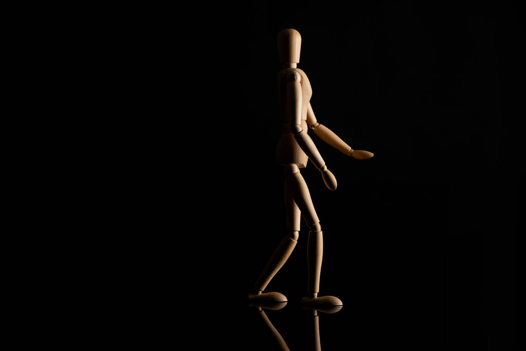 Bambola di legno che imita camminare su sfondo nero
 - Foto, immagini