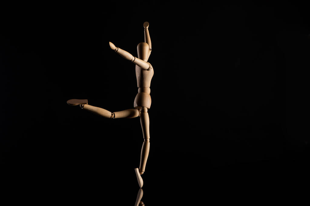 Marioneta de madera imitando el baile sobre fondo negro
 - Foto, Imagen