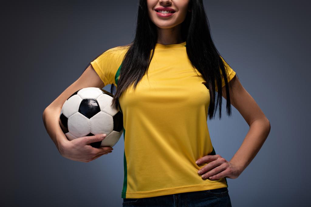 обрізаний вид красивої дівчини, що тримає футбольний м'яч на сірому
 - Фото, зображення