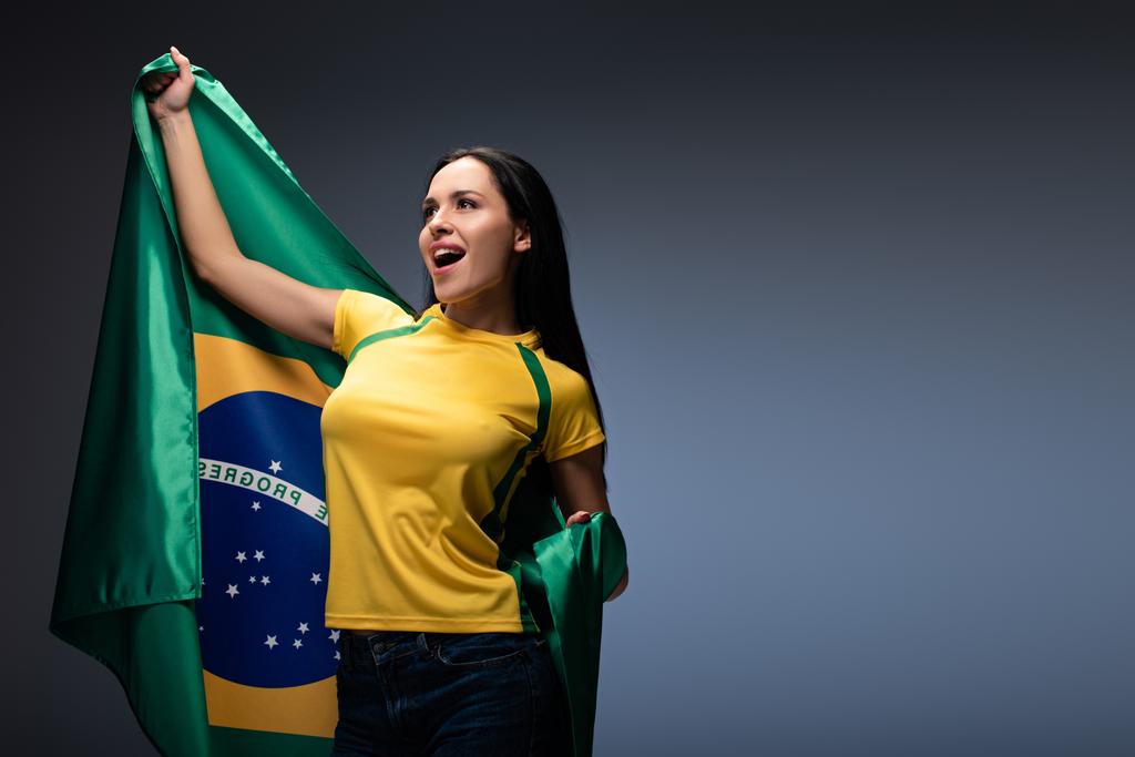 excitado fã de futebol feminino segurando bandeira brasileira em cinza
  - Foto, Imagem