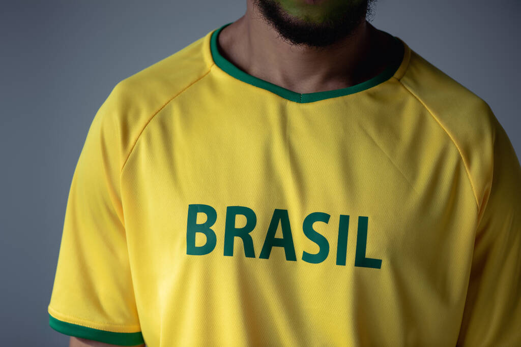 bijgesneden weergave van voetbal ventilator in geel t-shirt met braziliaans teken geïsoleerd op grijs - Foto, afbeelding
